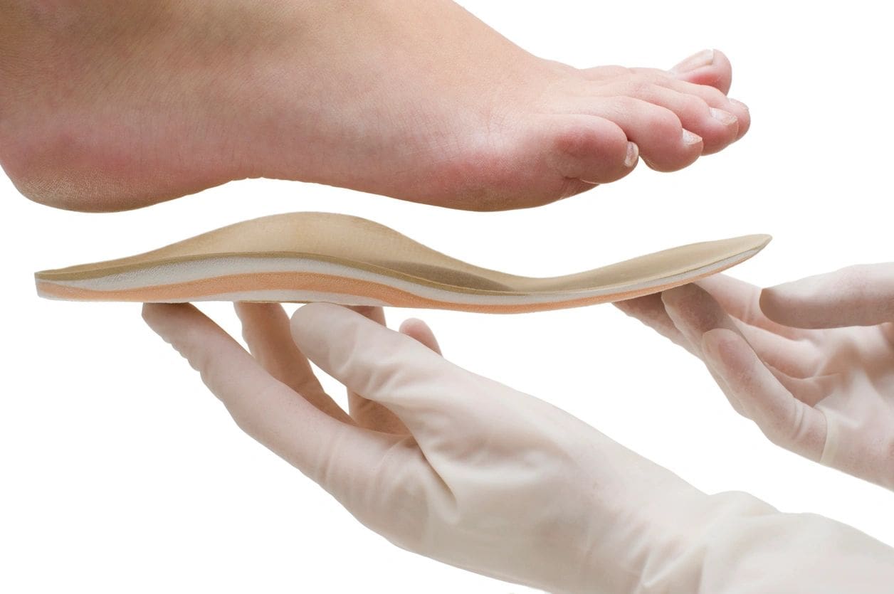 A person is holding an orthopedic insole over their foot.