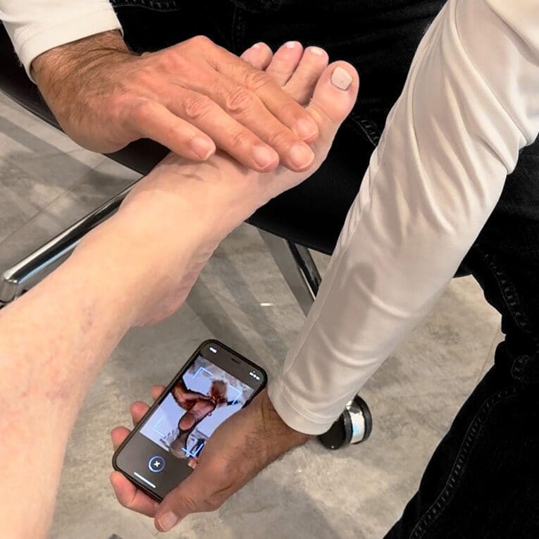 A man holding another mans hand while he is on his phone.